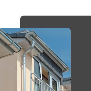 Silbernes, verzinktes Zambelli Sockelknie DN 100 am Fallrohr einer Dachrinne an Hausfassade.