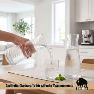 Hand gießt Wasser aus geriffelter 1L Glaskaraffe in Glas; zweite Karaffe auf Holztisch. Stilvolle Küchenausstattung.