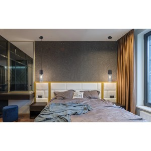 Moderne Pendelleuchte Annika, schwarz matt mit rauchfarbenem Glas, hängt über einem Bett im Schlafzimmer.