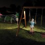Mr. Beams LED-Außenwandleuchte MB310 beleuchtet Garten mit Schaukel und spielendem Kind.