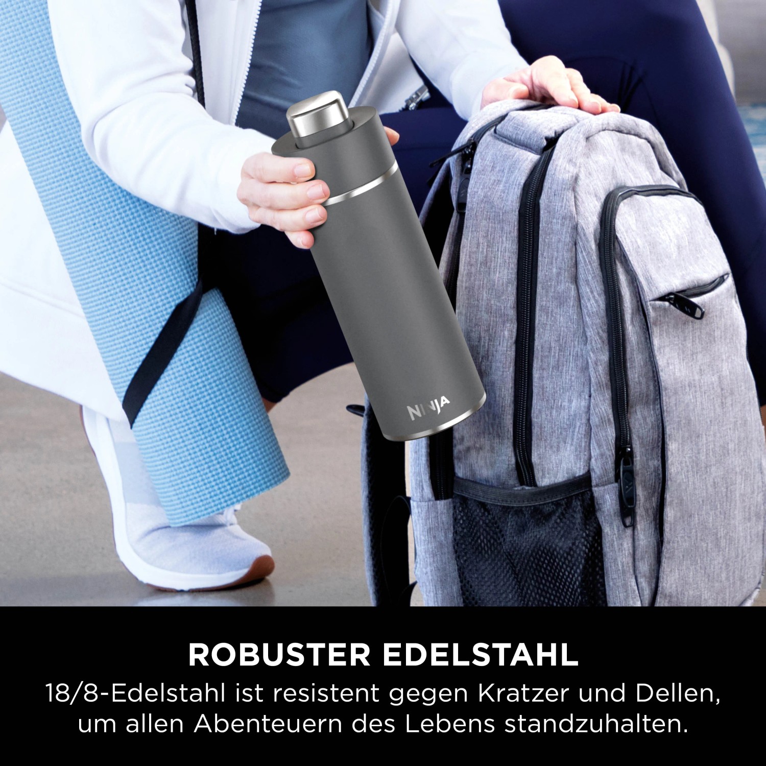 Graue Ninja Thirsti Trinkflasche (530 ml) neben Rucksack und Yogamatte.