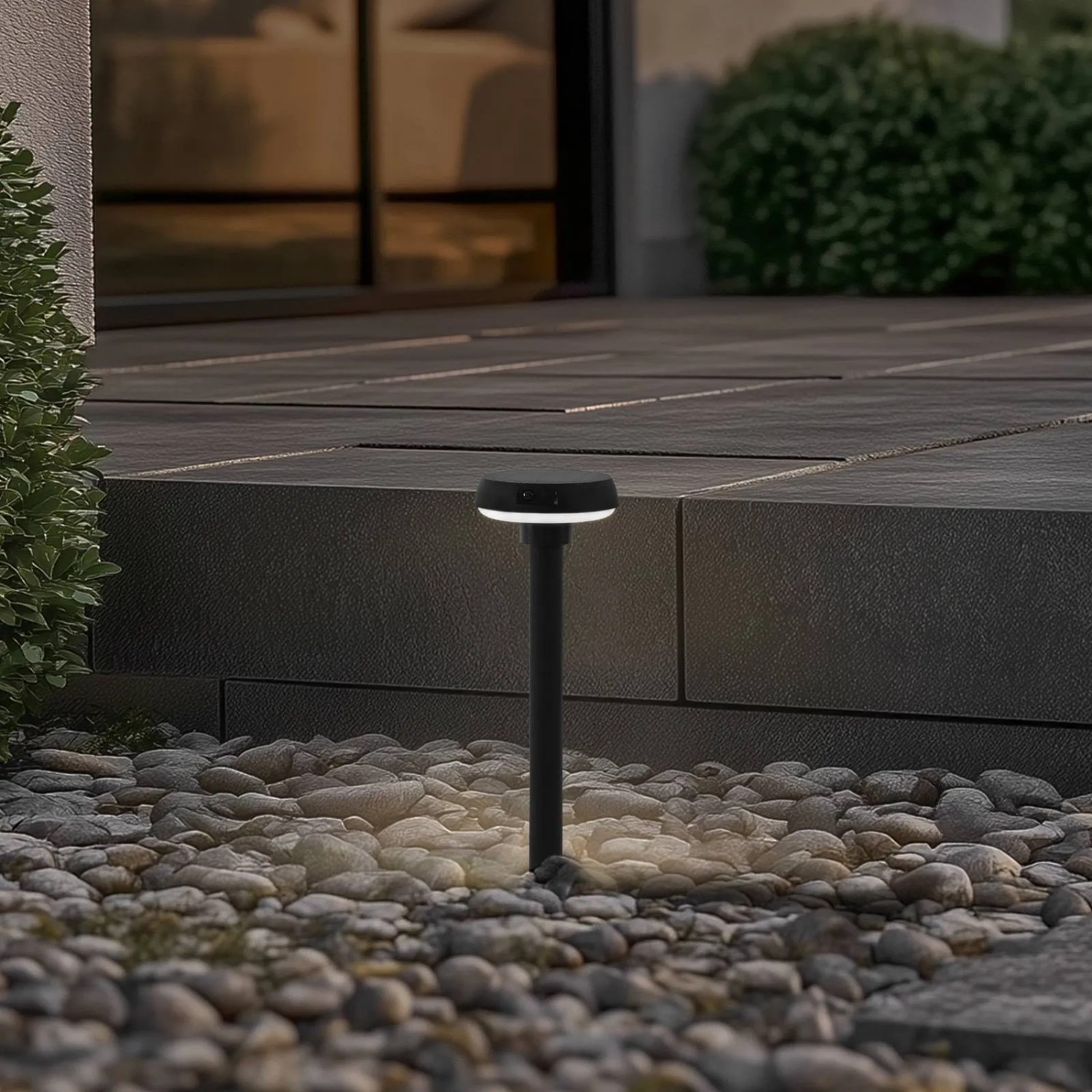 Schwarze Lindby LED Solarleuchte Brinca mit Bewegungsmelder im Garten.