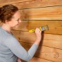 Frau trägt farblose Xyladecor Holzschutz-Lasur auf Holzzaun auf.