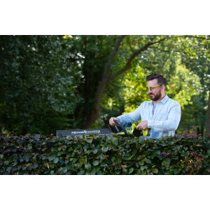 Mann schneidet Hecke mit Ryobi Akku-Heckenschere RY18HT55A-120. Inkl. Akku und Ladegerät.