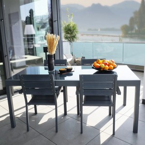 Ausziehbarer, hellgrauer Home Deluxe Gartentisch Sol aus Glas mit Stühlen auf einer Terrasse.