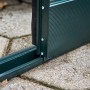 Detailaufnahme: Grüne Schiebetür mit bodentiefer Schwelle des Halls Gewächshaus GardenRoom.