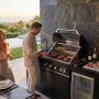 Buschbeck Outdoorküche Liverpool Schwarz mit Grill, Spüle, Kühlschrank und Personen.