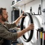 Mann hängt Fahrradreifen an schwarzem U-Wandhaken in Werkstatt. Robustes 12-teiliges Haken-Set für Werkzeuge und Ordnung in Garage.