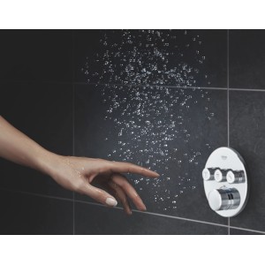 Grohe Thermostat Grohtherm SmartControl Chrom mit Wasserstrahl und Hand auf runder Wandrosette.