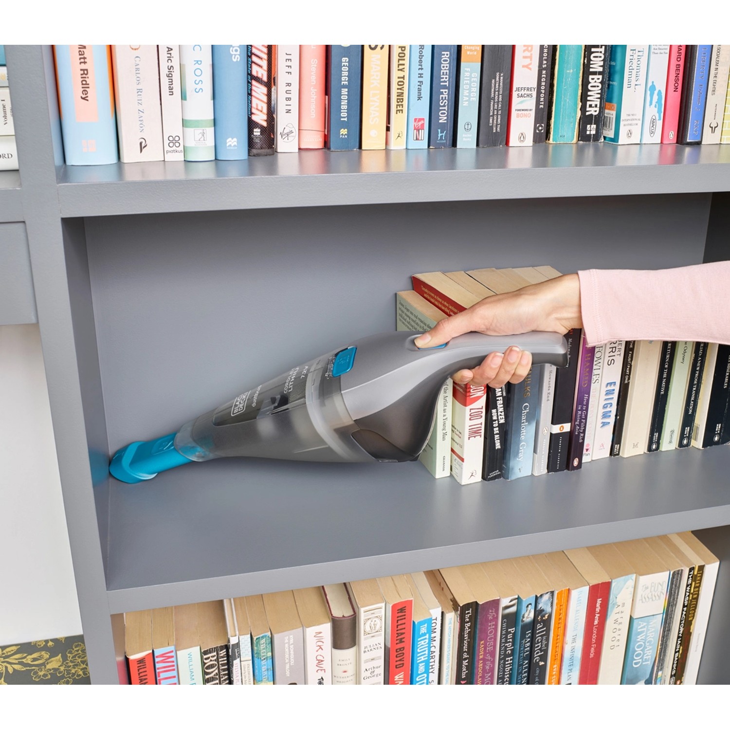 Black+Decker Akku-Handstaubsauger NVC215WA in grau/blau bei der Reinigung eines Bücherregals.
