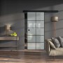 Moderne Glasschiebetür mit satiniertem Glas und schwarzem Rahmen als Raumteiler.