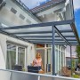 Moderne, anthrazitfarbene Terrassenüberdachung aus Aluminium mit Polycarbonatplatten am Haus.