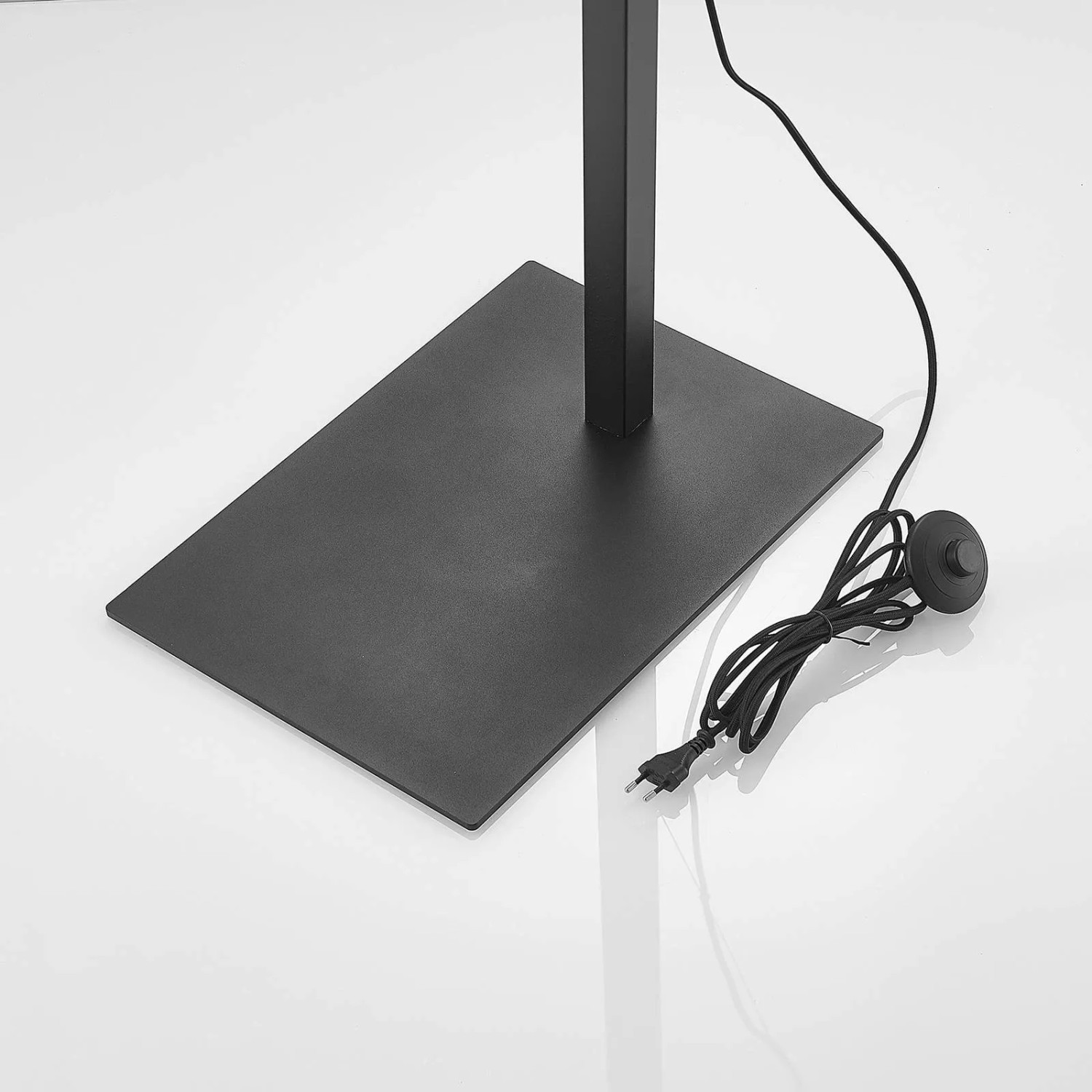 Detailaufnahme: Schwarze Arcchio Bogenlampe Mossa mit Fußschalter und Stromkabel.