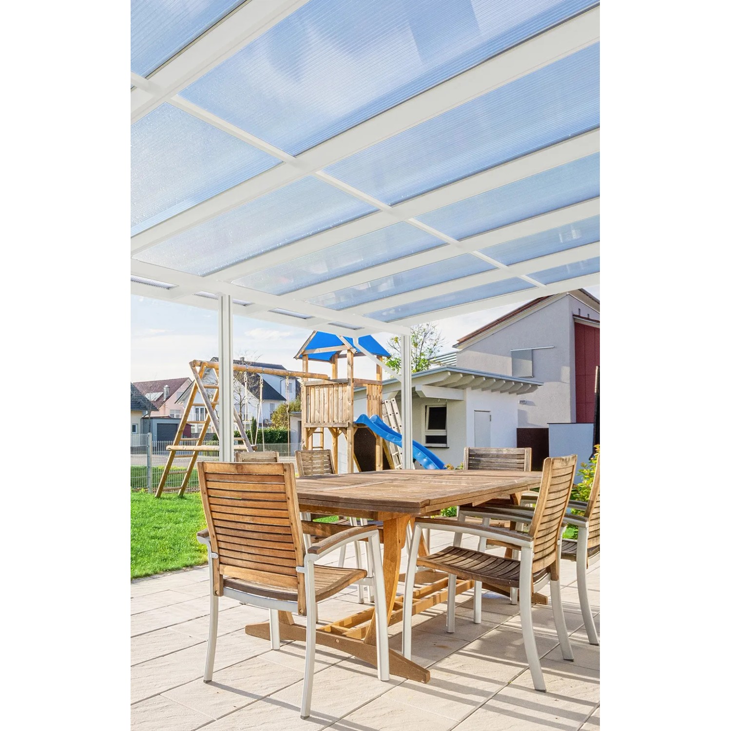 Helle Gutta Terrassenüberdachung Premium, weiße Stegplatten, Gartenmöbel und Spielplatz im Hintergrund.