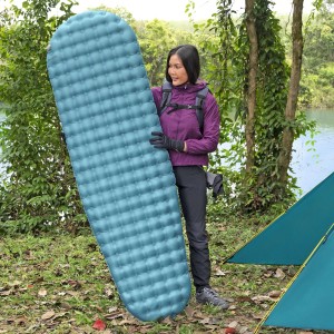 Frau hält blaue Single-Isomatte AlpineLite™ (183x51x7,5 cm) von Bestway im Camping-Umfeld.
