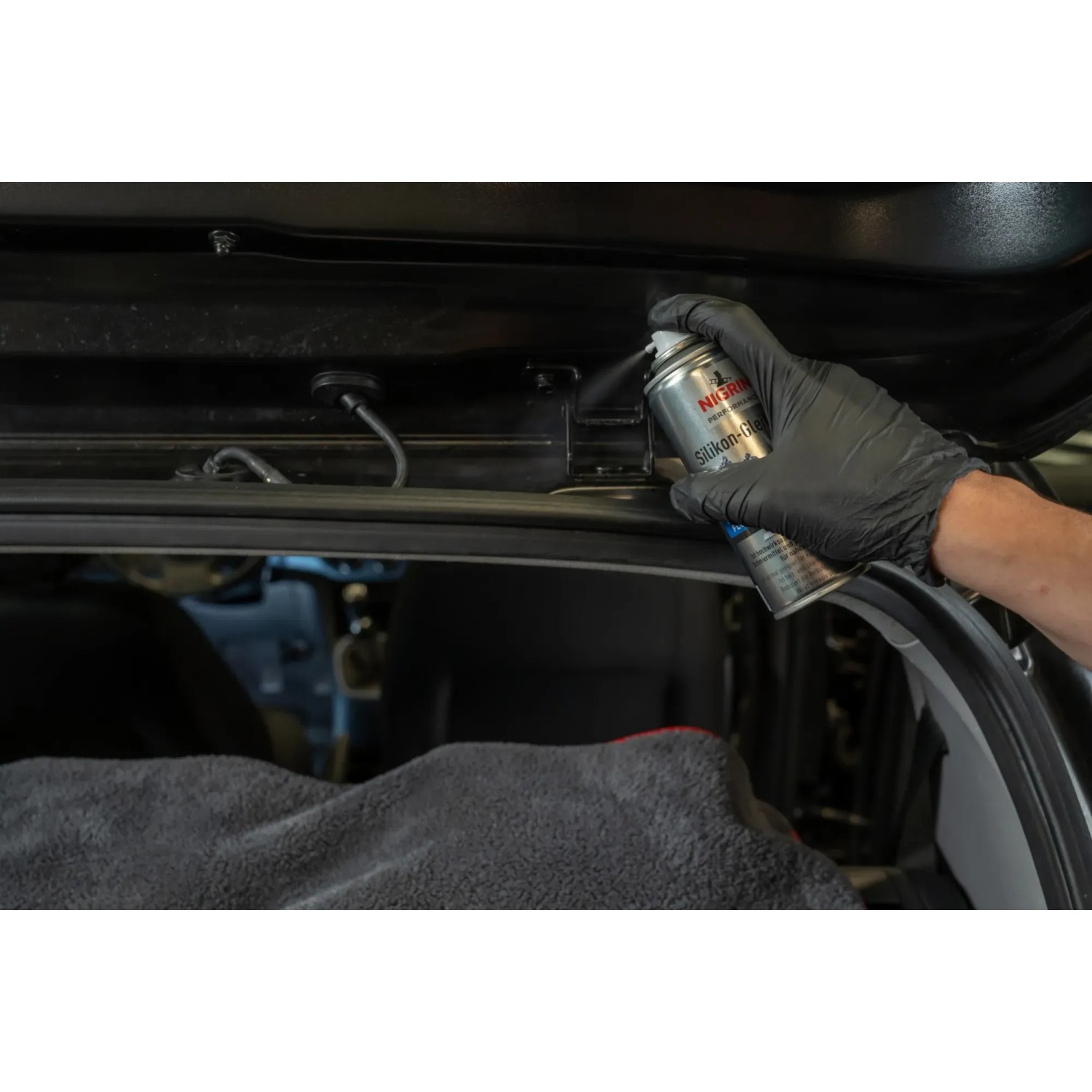 Anwendung von Nigrin Silikon-Gleitspray HyBrid zur Autopflege im Innenraum.