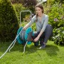 Frau bedient Gardena CleverRoll M Schlauchwagen im Garten. Schlauchaufroller mit Schlauch.