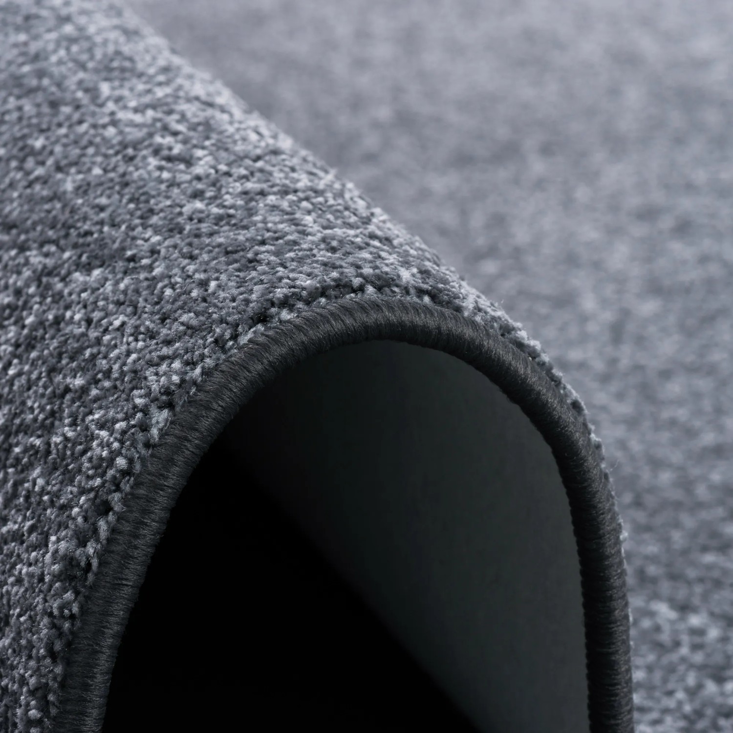 Detailansicht: Runder, anthrazitfarbener Snapstyle Teppich Shine aus weichem Velours.