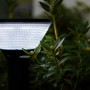 Schwarze Lutec LED Solar-Wegeleuchte Karlo, 45 cm hoch, mit hellem Licht zwischen Pflanzen.