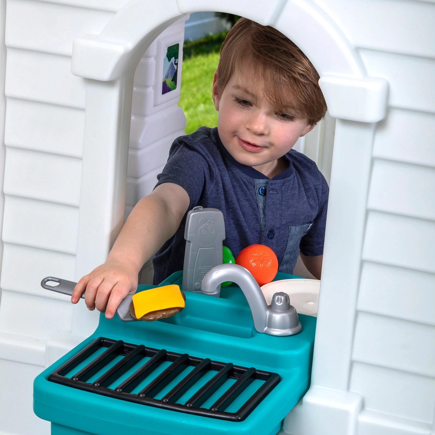 Kind spielt im Step2 Spielhaus Neat & Tidy Cottage mit Küche und Zubehör.