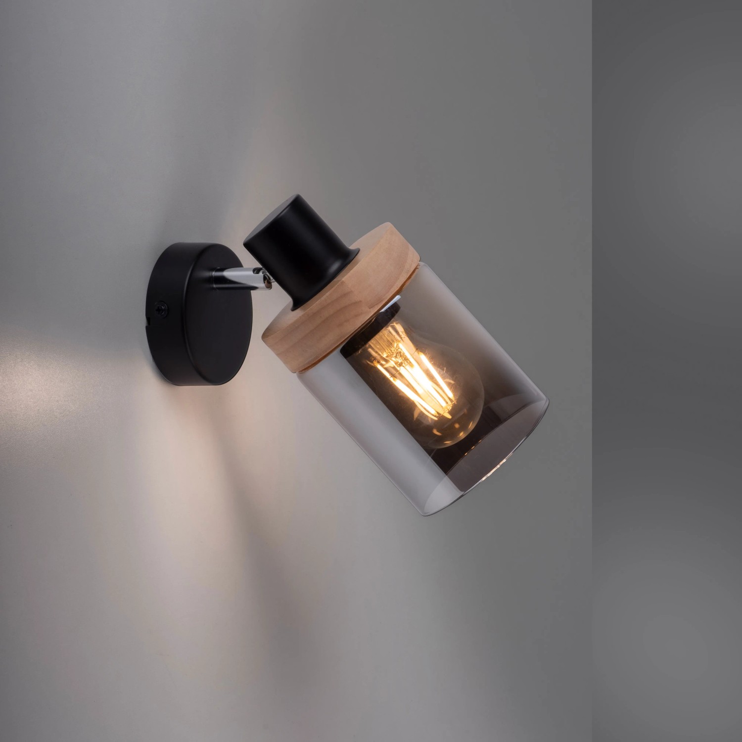 Schwarze Wandleuchte Pasqual mit Rauchglas-Schirm und Holzdetails. Flexibler Spot für optimale Ausleuchtung.