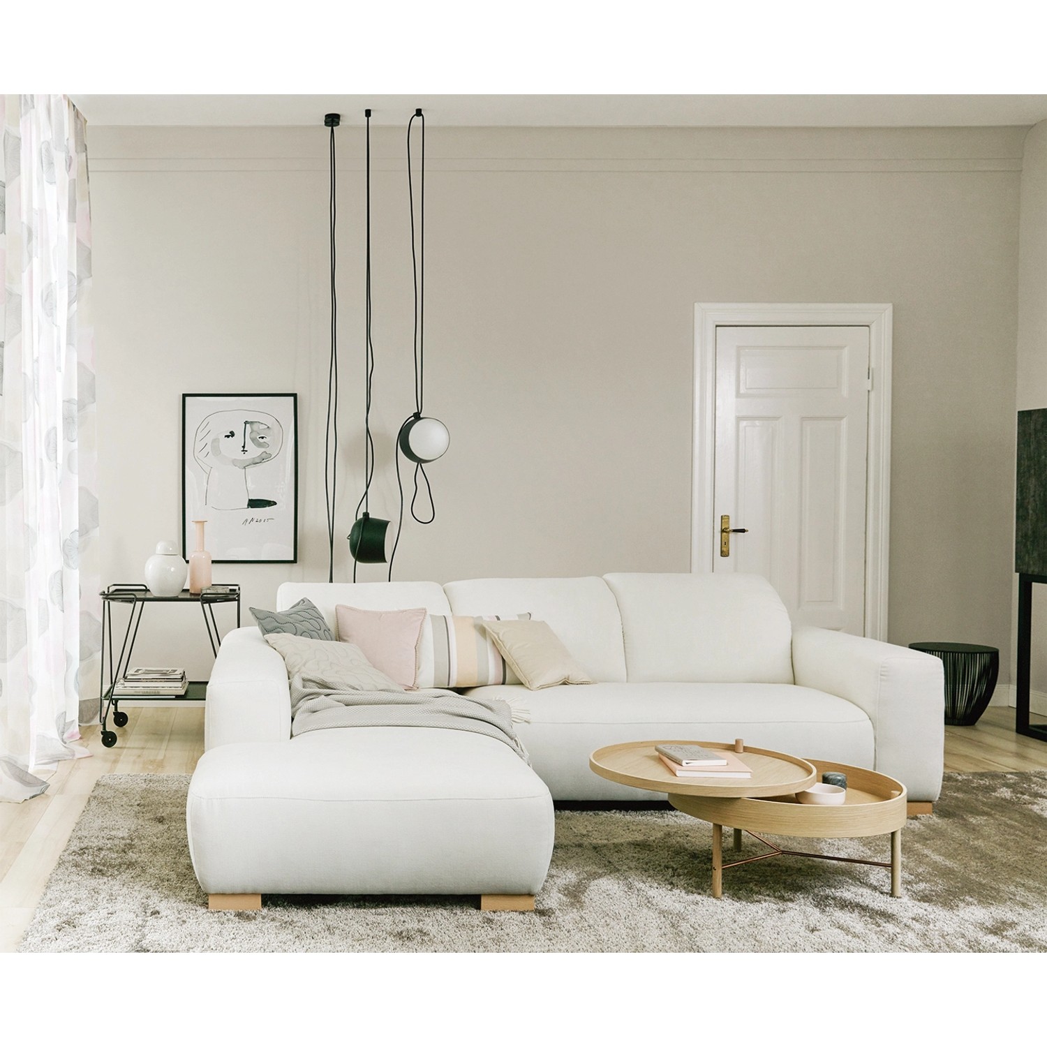 Wohnraum mit weißer Couch, Tisch und Deko. Schöner Wohnen Trendfarbe im Hintergrund.