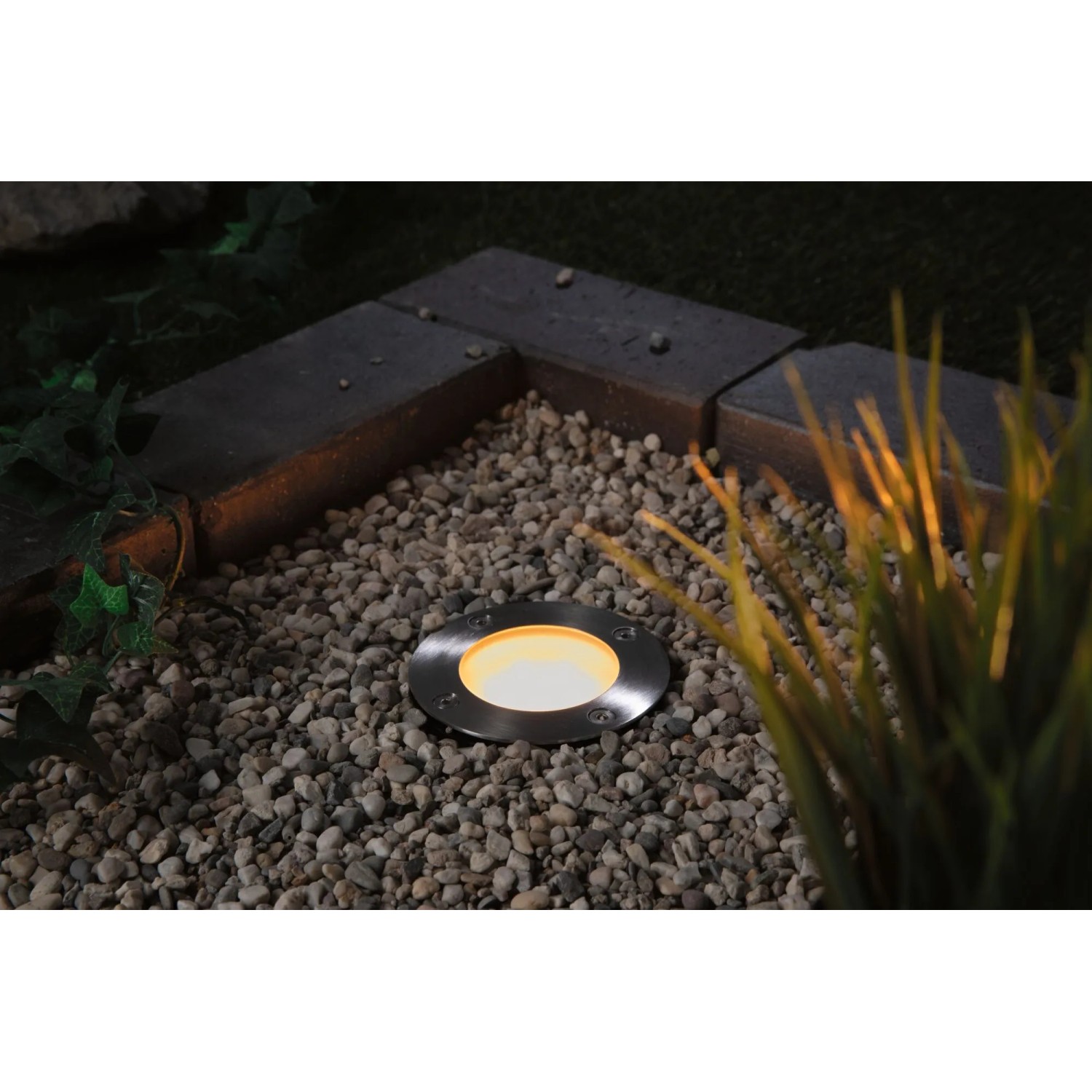 Paulmann LED-Bodeneinbaustrahler Plug & Shine 24V ZigBee im Garten, umgeben von Kies.