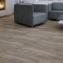 Verlegtes Feinsteinzeug Tizura in Braun mit Holzoptik im Wohnzimmer mit Kamin und grauer Couch.