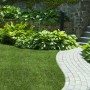 Sattes Grün: Primaflor Kunstrasen Jazz im Garten mit Steinweg und Bepflanzung.