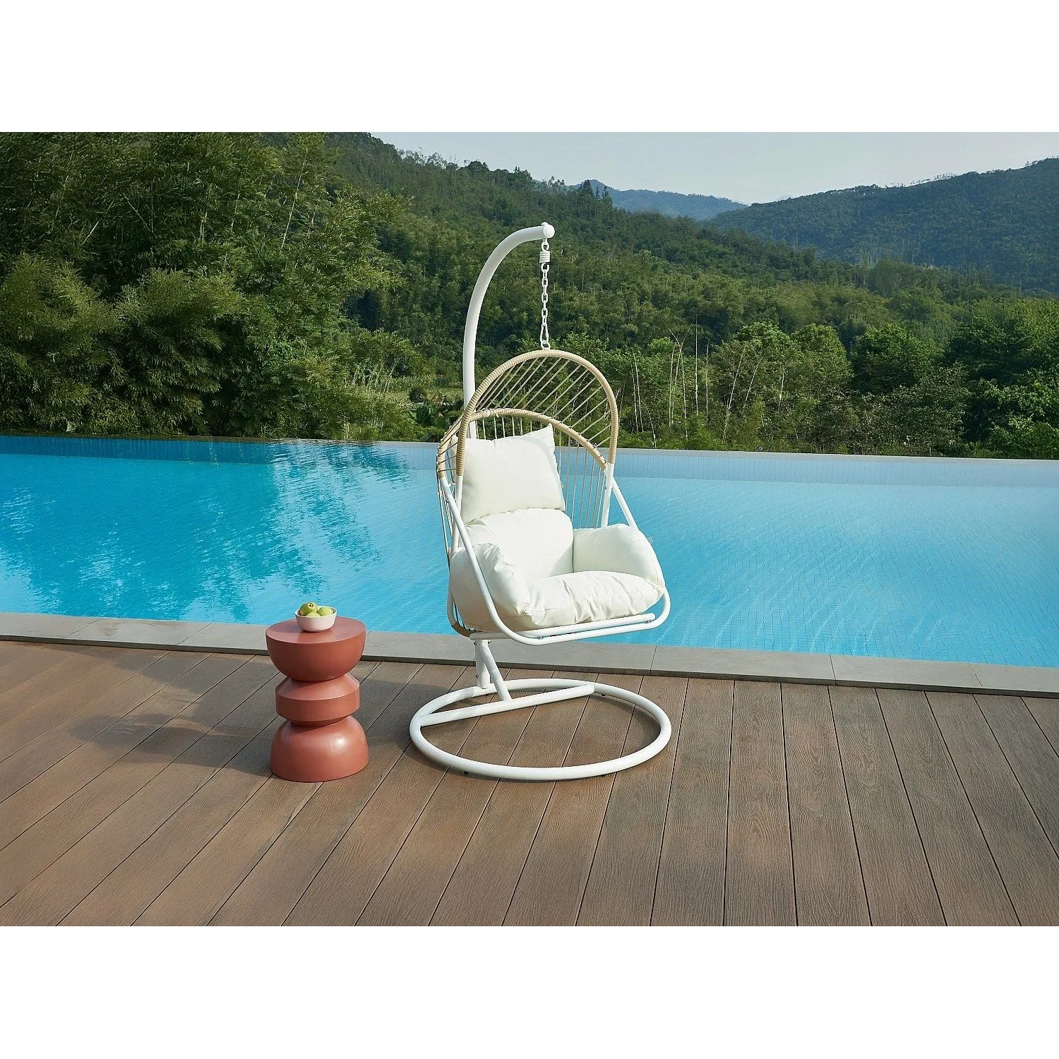 Vente-unique Hängesessel Lutus, hell naturfarben, mit weißem Gestell und Kissen auf Holzterrasse am Pool.