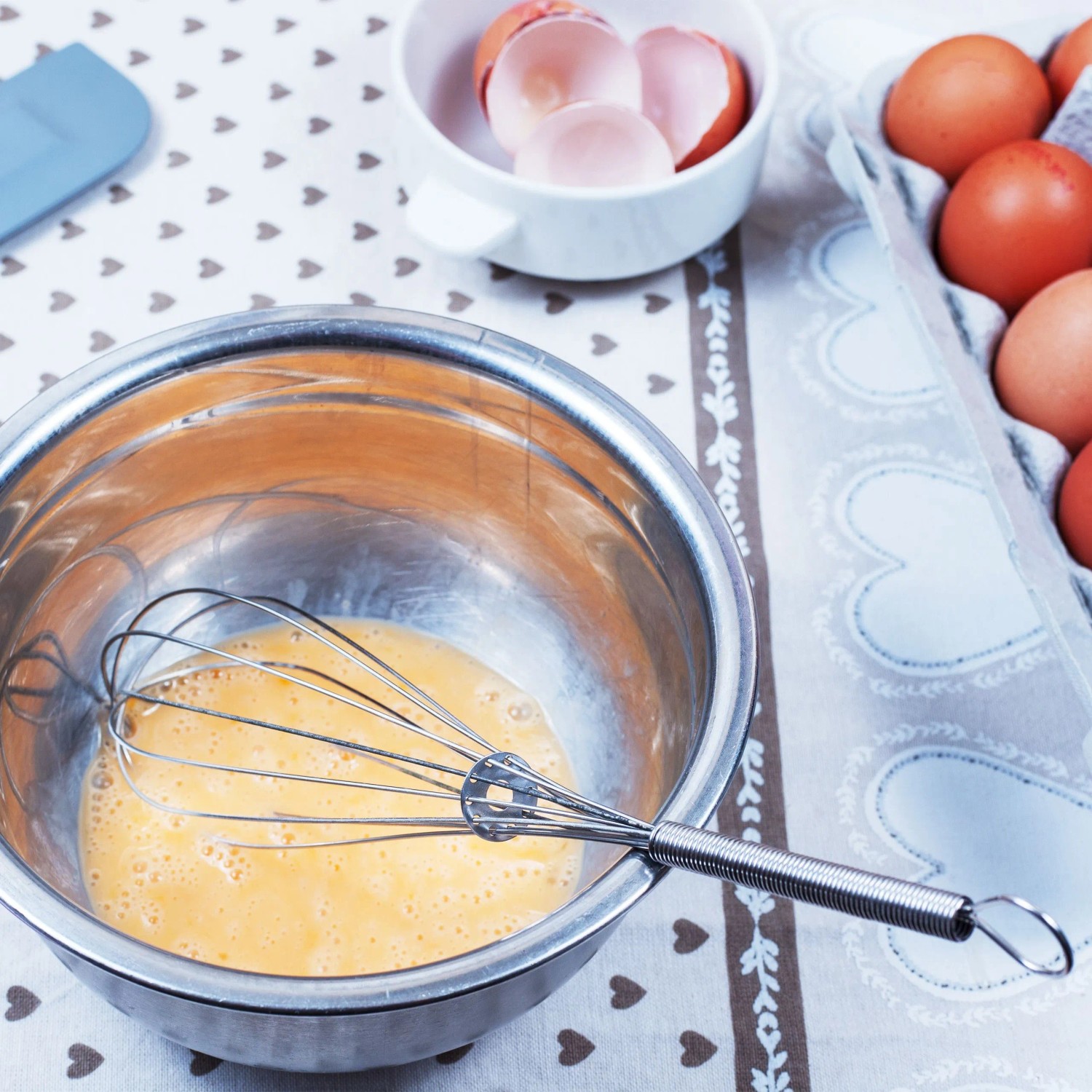 Silberne Edelstahl Rührschüssel mit Schneebesen und verquirlten Eiern. Ideal für Backen und Kochen.