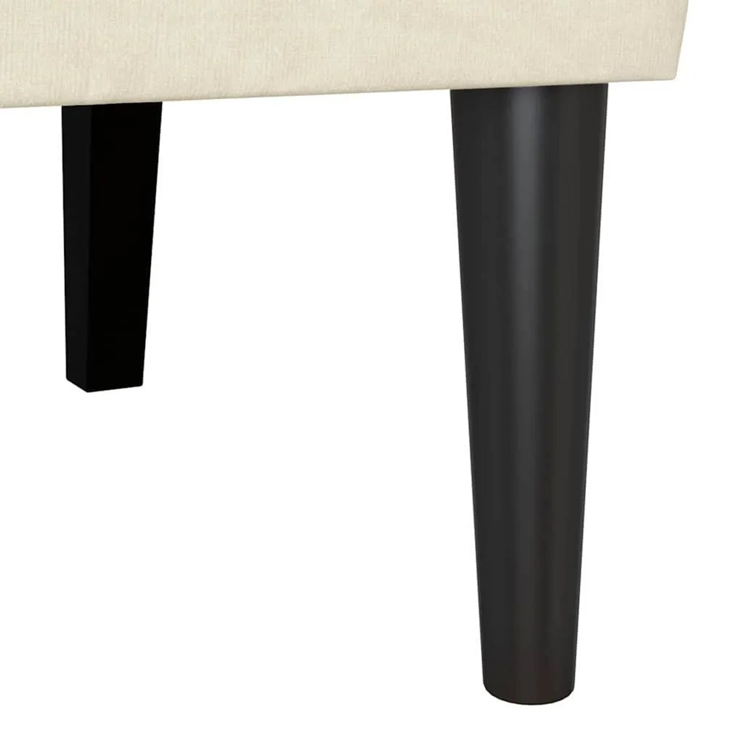Cremefarbene Samt Chesterfield Bank. Dunkle, konische Holzbeine und cremefarbene Polsterung der Sitzbank.