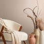 Beige Marburg Vliestapete Uni Textiloptik an Wand hinter Sessel und Vasen.