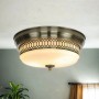 Messingfarbene Deckenlampe mit weißem Glasschirm, geeignet für Badezimmer.