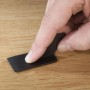 Hand glättet mit schwarzem Spachtel eine Ausbesserung auf hellem Laminat oder Parkett. Westfalia Reparatur-Set.