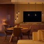Philips Hue Filament Lampe E27 in Wohnraum-Szene mit Esstisch und Sofa.