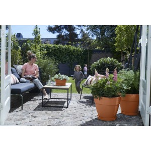 Elho Blumentopf Vibia Campana, Ø 47 cm, Terra, im Garten mit Pflanzen und spielenden Kindern.