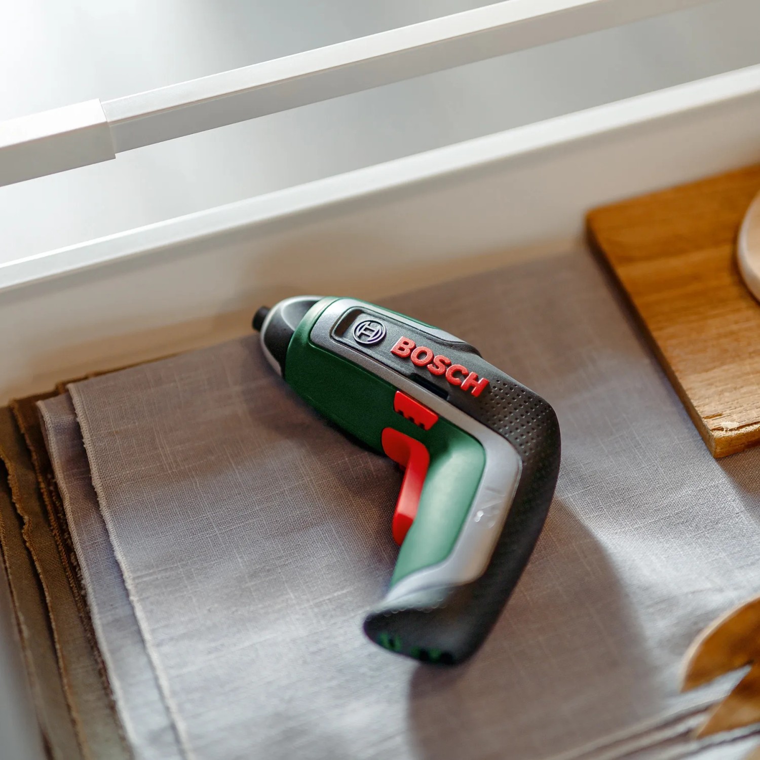 Bosch IXO 7 Akkuschrauber, Set mit Akku, Ladekabel und Aufsätzen, im Regal.