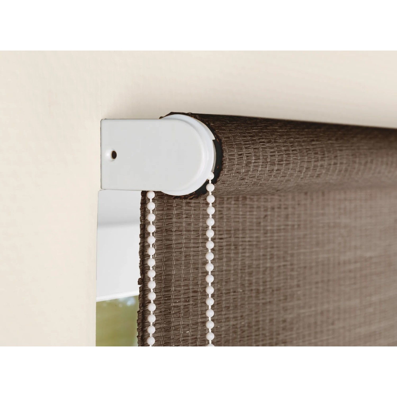 Detailaufnahme: Dunkelbraunes OBI Naturfaser-Rollo Camas mit Seitenzug und weißer Halterung.