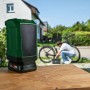 Grüner Bosch UniversalSpeaker 18V-1 Akku-Bluetooth-Box auf Holztisch, mit 18V Akku, im Freien bei Fahrradreparatur.
