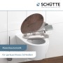 Schütte WC-Sitz Dark Wood mit Absenkautomatik auf weißer Toilette vor Wandfliesen.