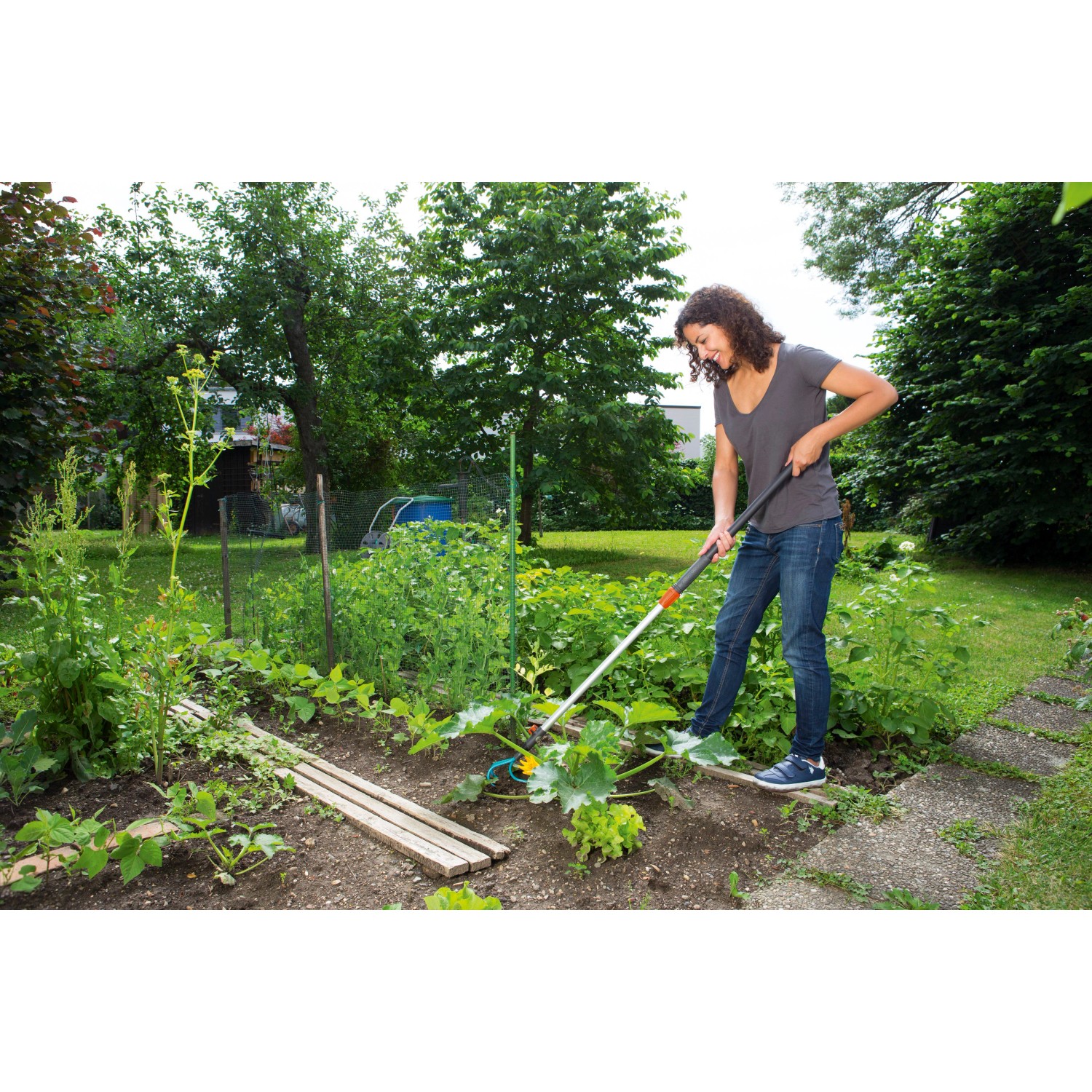 Frau arbeitet mit Gardena combisystem-Teleskopstiel im Garten. Das Kombisystem ist optimal für bequemes Arbeiten.