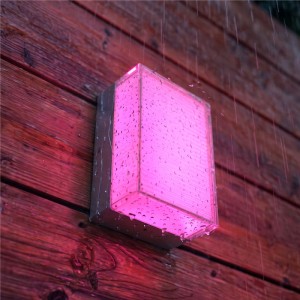 Philips Hue Semeru Wandleuchte, rechteckig, leuchtet pink an Holzwand im Regen. Wetterfeste Außenleuchte mit Farbwechsel.