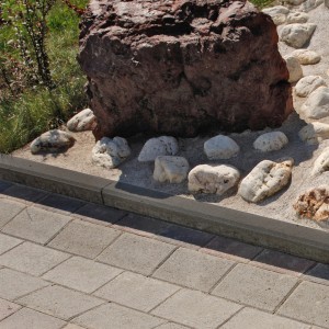 Anthrazit Tiefbordstein aus Beton als Beetbegrenzung im Garten. Randstein für Einfassung von Wegen und Beeten.