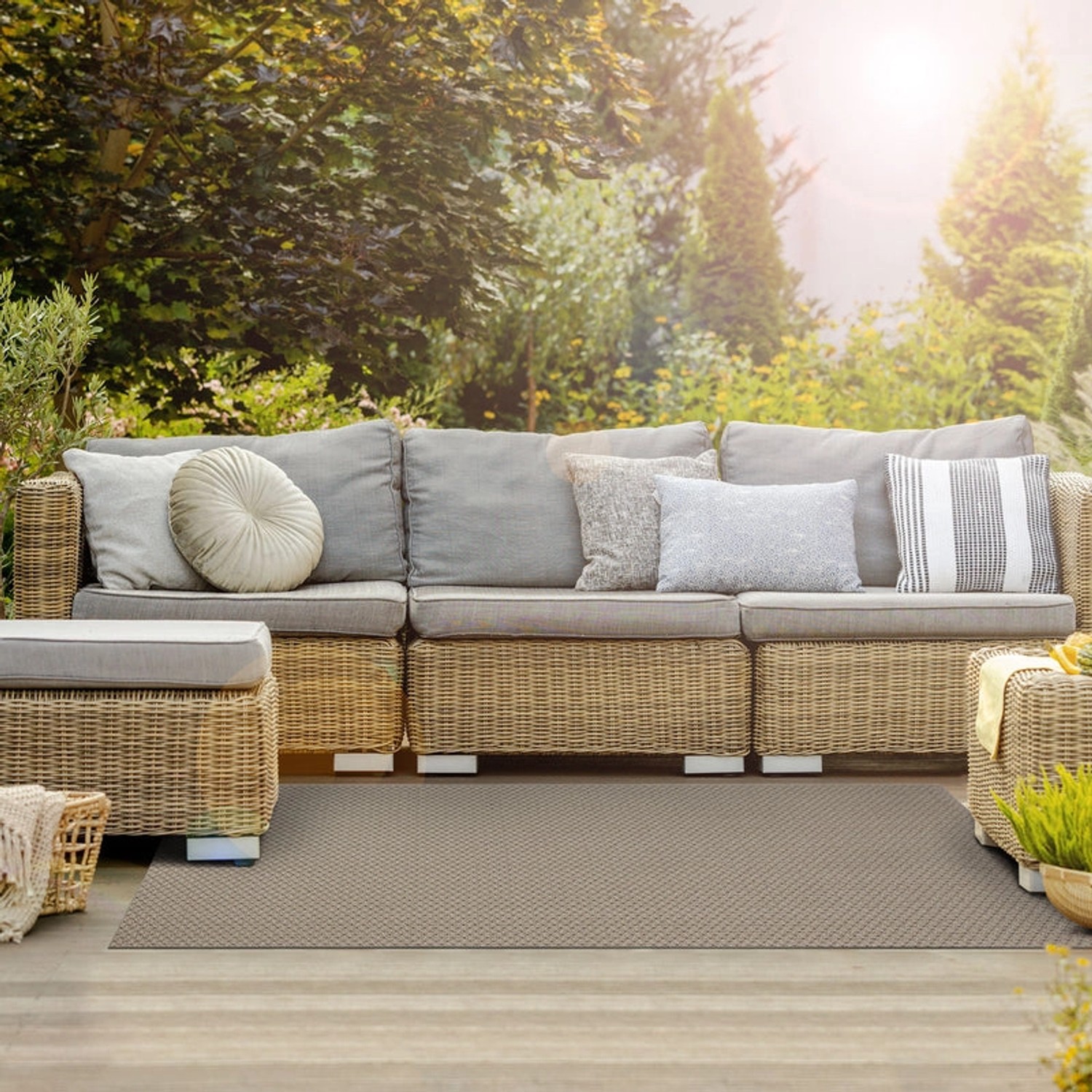 Wetterfester, beiger Outdoor Teppich 90x700cm auf Terrasse vor Rattansitzgruppe.