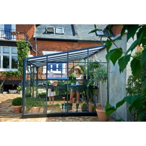 Juliana Gewächshaus Veranda 12 Anthrazit mit Pflanzen und Gärtnerin im Garten.