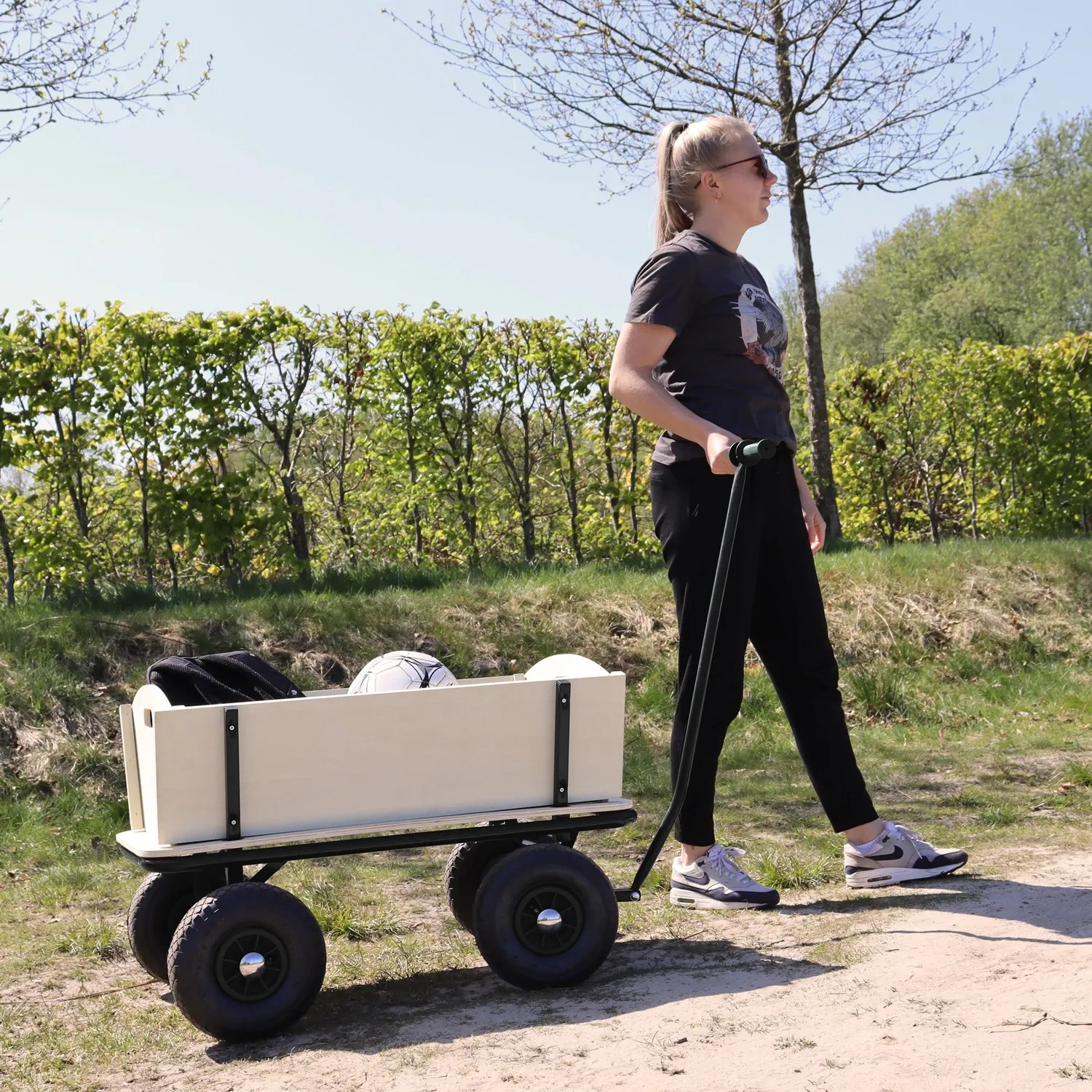 Schwarzer Sunny Bollerwagen Billy Beach Wagon mit Luftreifen und Holzaufbau im Einsatz.