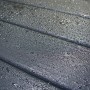 Detailaufnahme: Anthrazitfarbene Holzoberfläche des Weka Designhauses mit Wassertropfen.