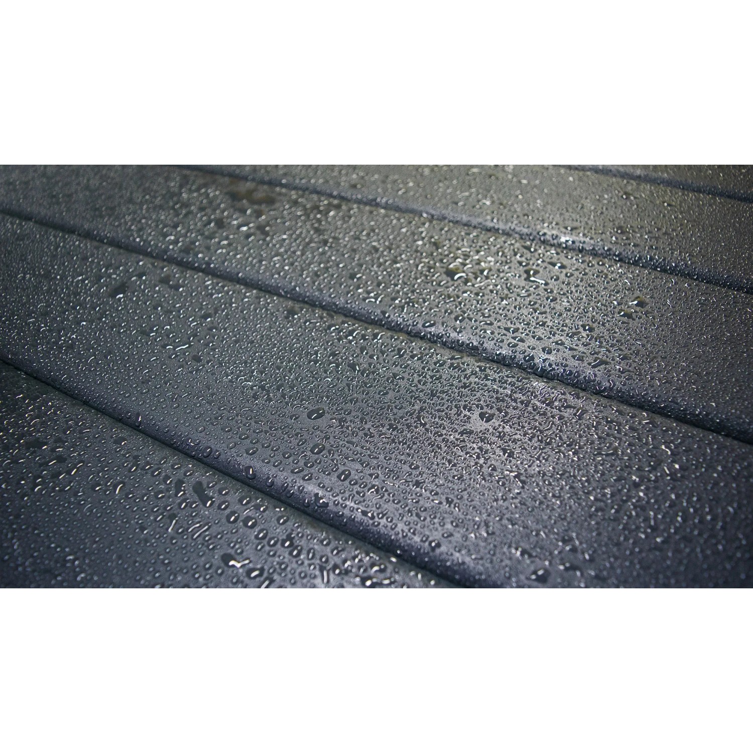 Detailaufnahme: Anthrazitfarbene Holzoberfläche des Weka Designhauses mit Wassertropfen.