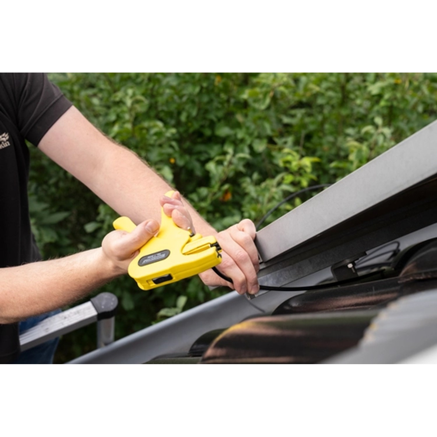 Gelb-schwarze WEICON Abisolierzange No.7 Solar beim Abisolieren eines Kabels auf einem Dach.